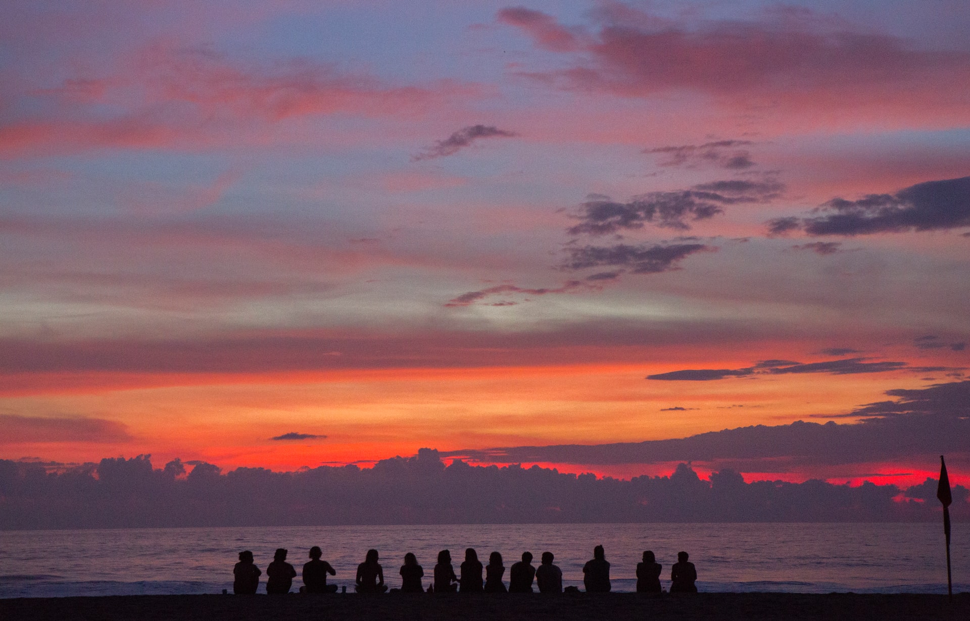 people sitting on seashore as sunsets