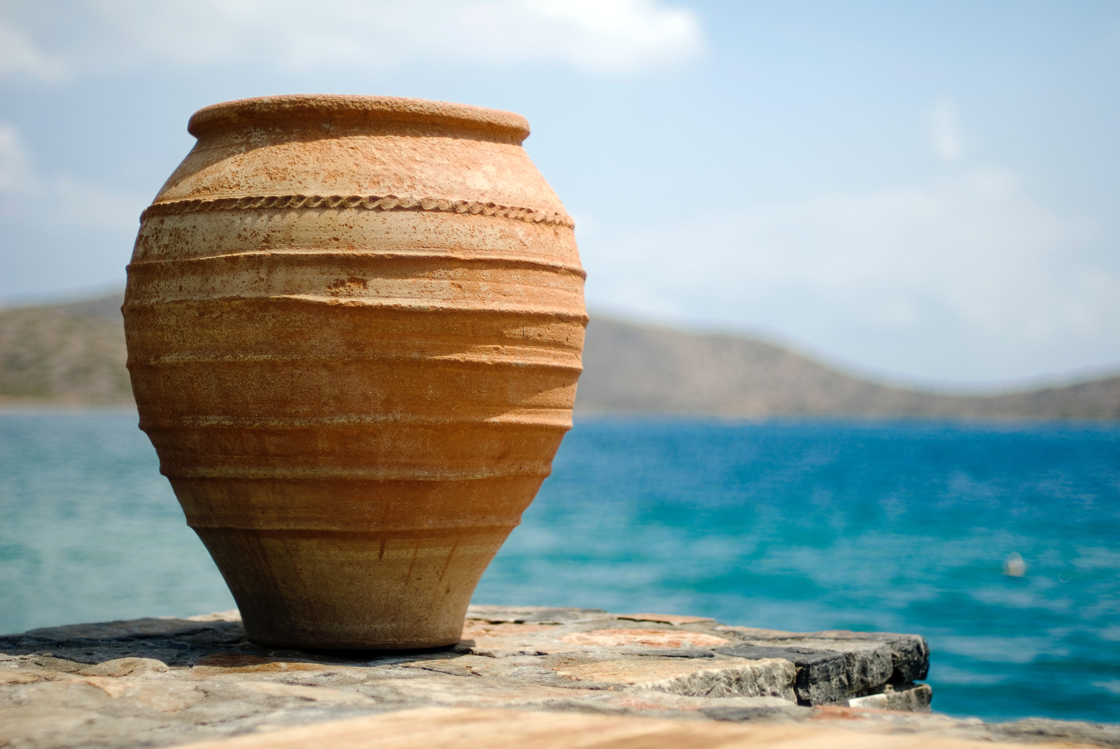brown clay pot on white with water in background